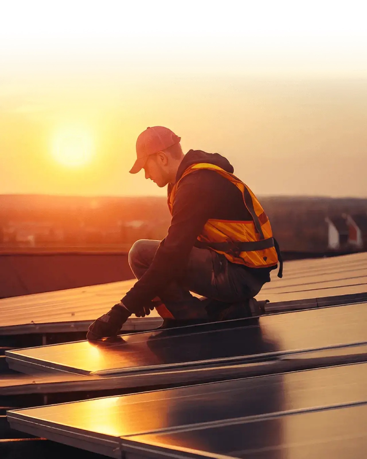 Instalador fixando placas solares em um telhado ao pôr do sol